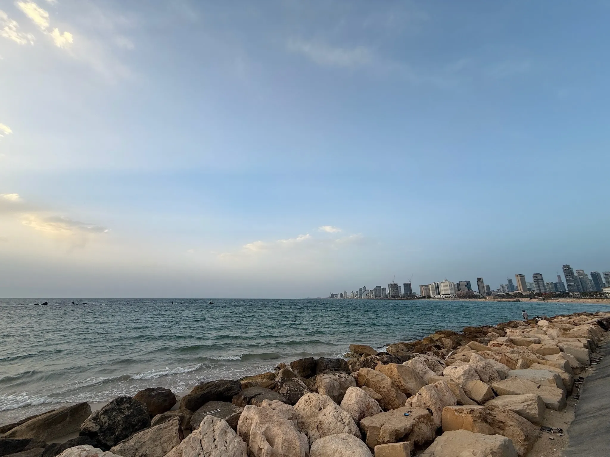 Breakwater rocks along the Mediterranean, with the Tel Aviv skyline on the horizon